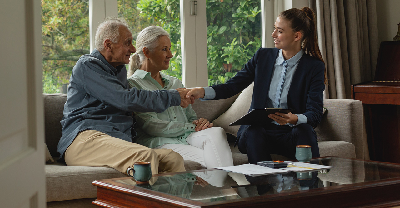 active senior man shaking hands with real estate agent in living room