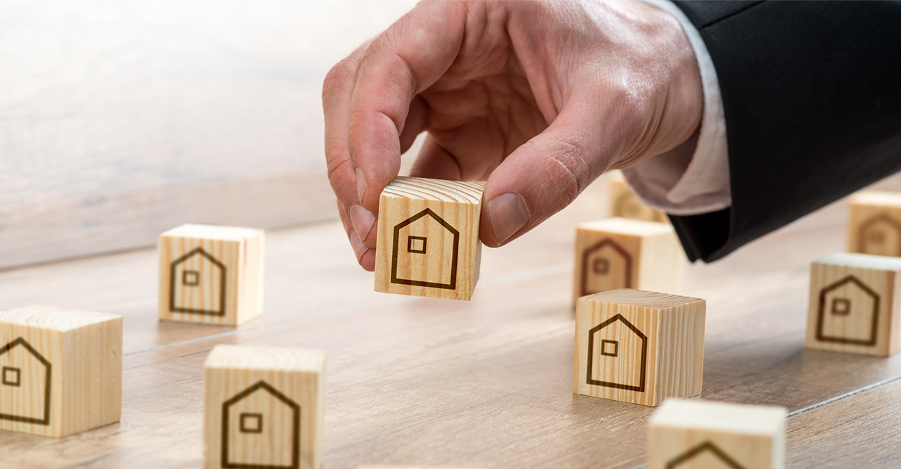 man arranging wooden cubes with house drawings