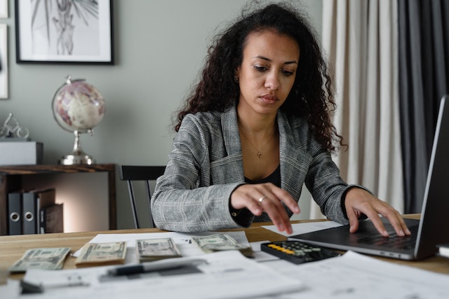 woman at desk with calculator, money, and documents