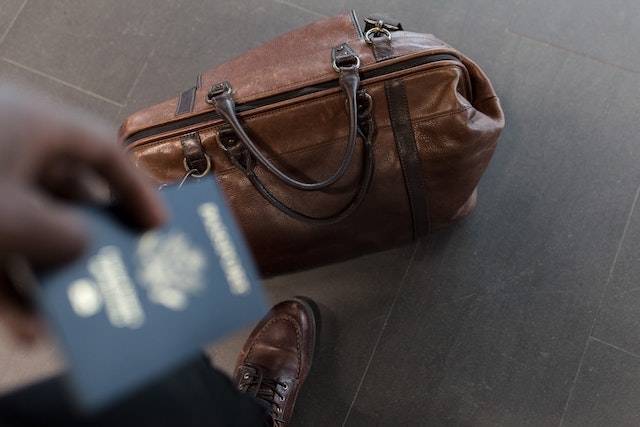 person holding passport next to luggage