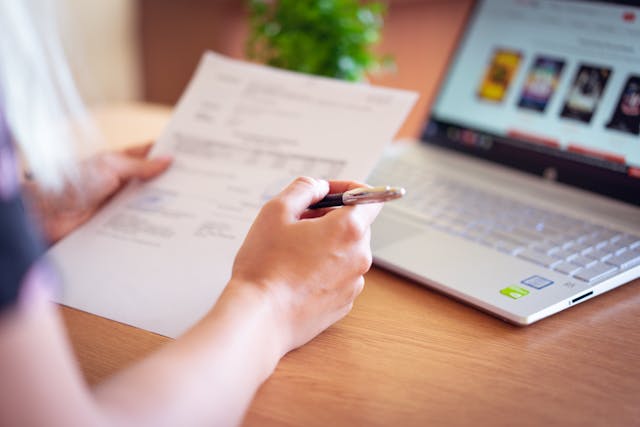 person looking at paper and computer