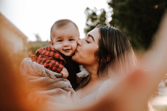 young woman kissing baby on cheek