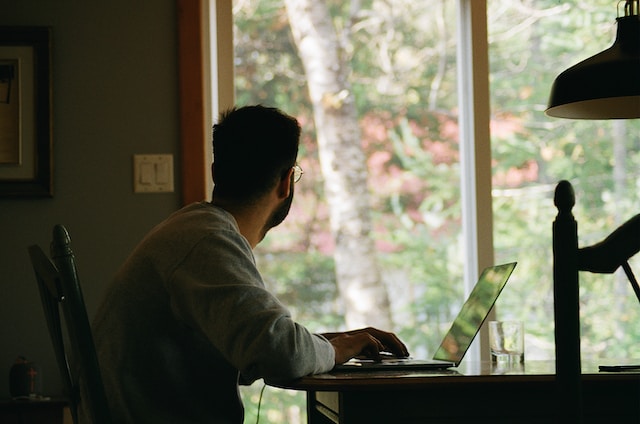 man looking our window on laptop