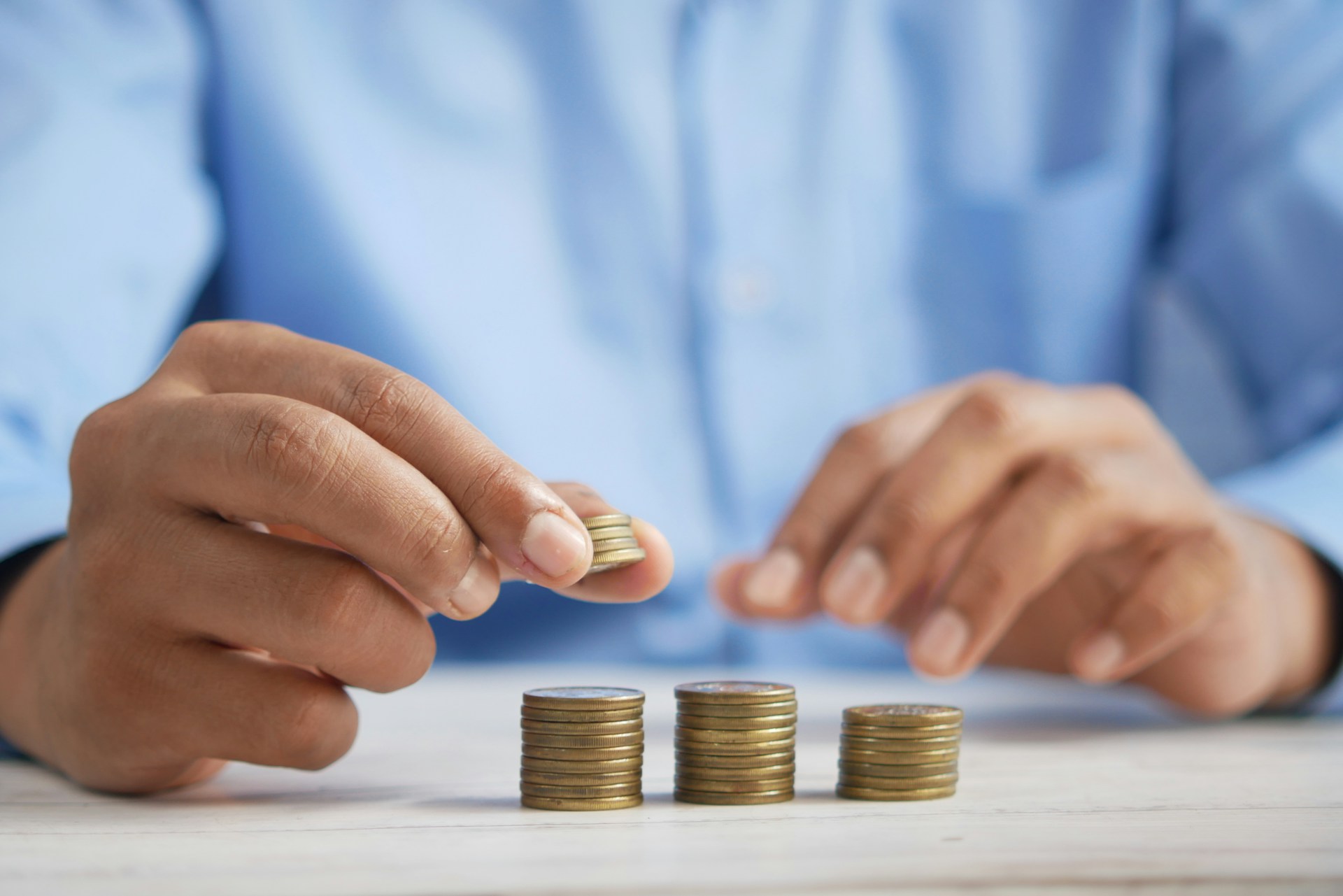 man in blue shirt stacking coins