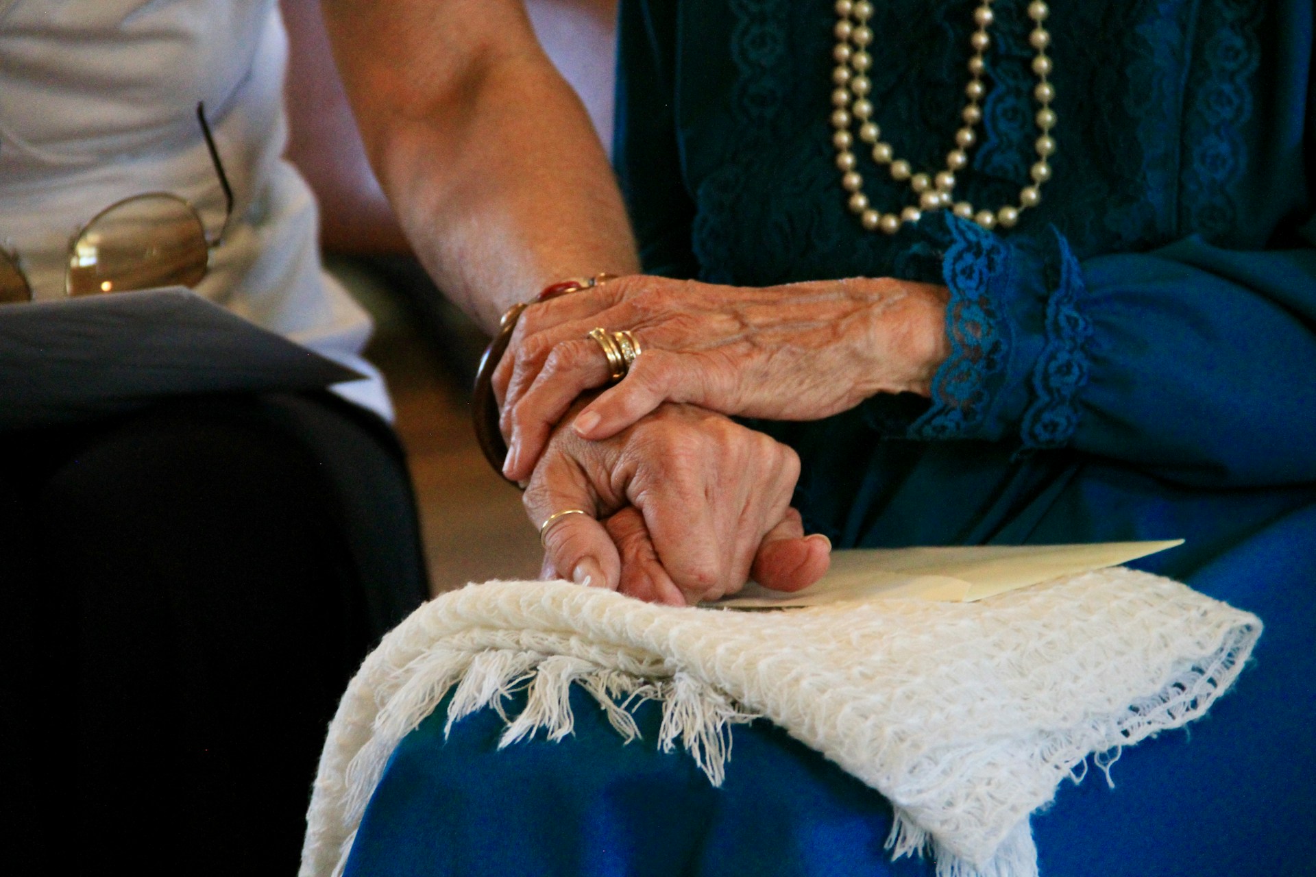 elderly woman holding hands with younger woman